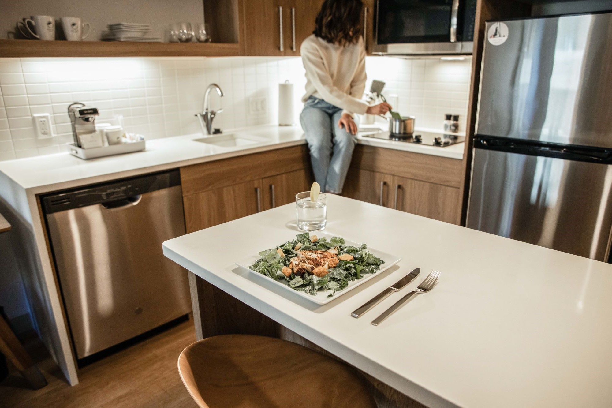 Guest sitting on kitchen counter while cooking and a meal served on a kitchen table.